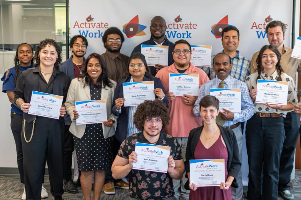 A group of smiling people standing in front of an ActivateWork-branded backdrop, holding certificates of completion for the Software Development bootcamp