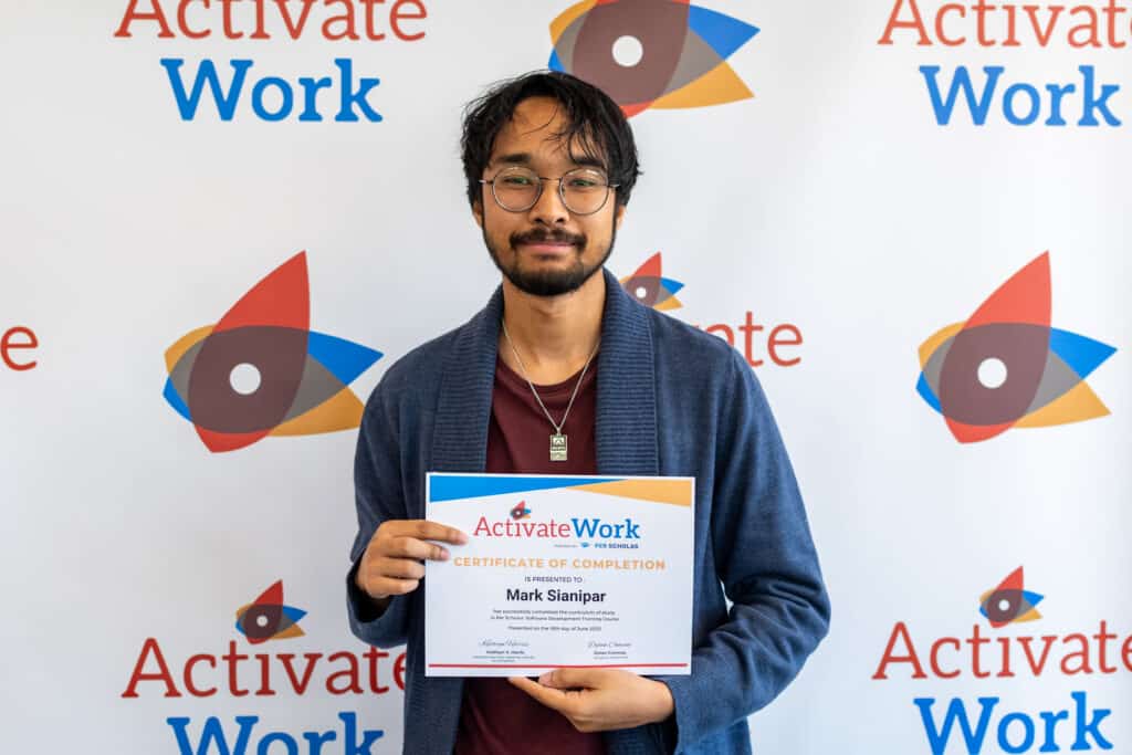 Mark Sianipar holding his Certificate of Completion in front of an ActivateWork-branded backdrop