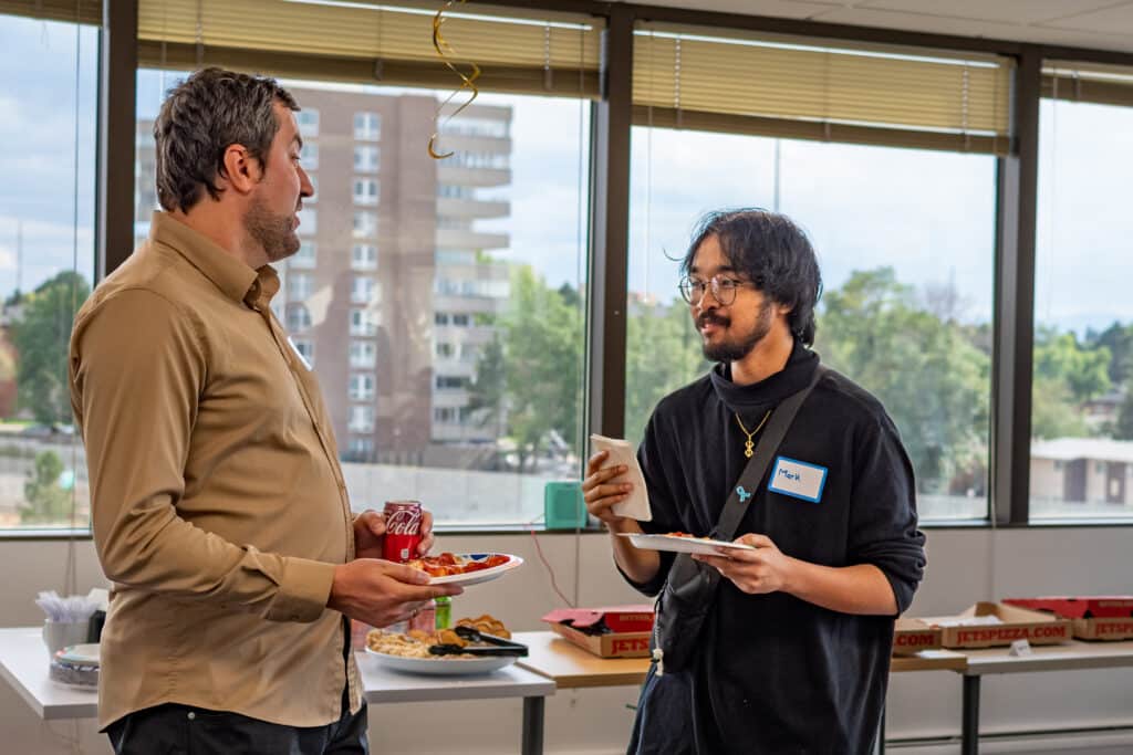 Mark chatting with a fellow ActivateWork graduate at an Alumni Pizza Party in late 2025.