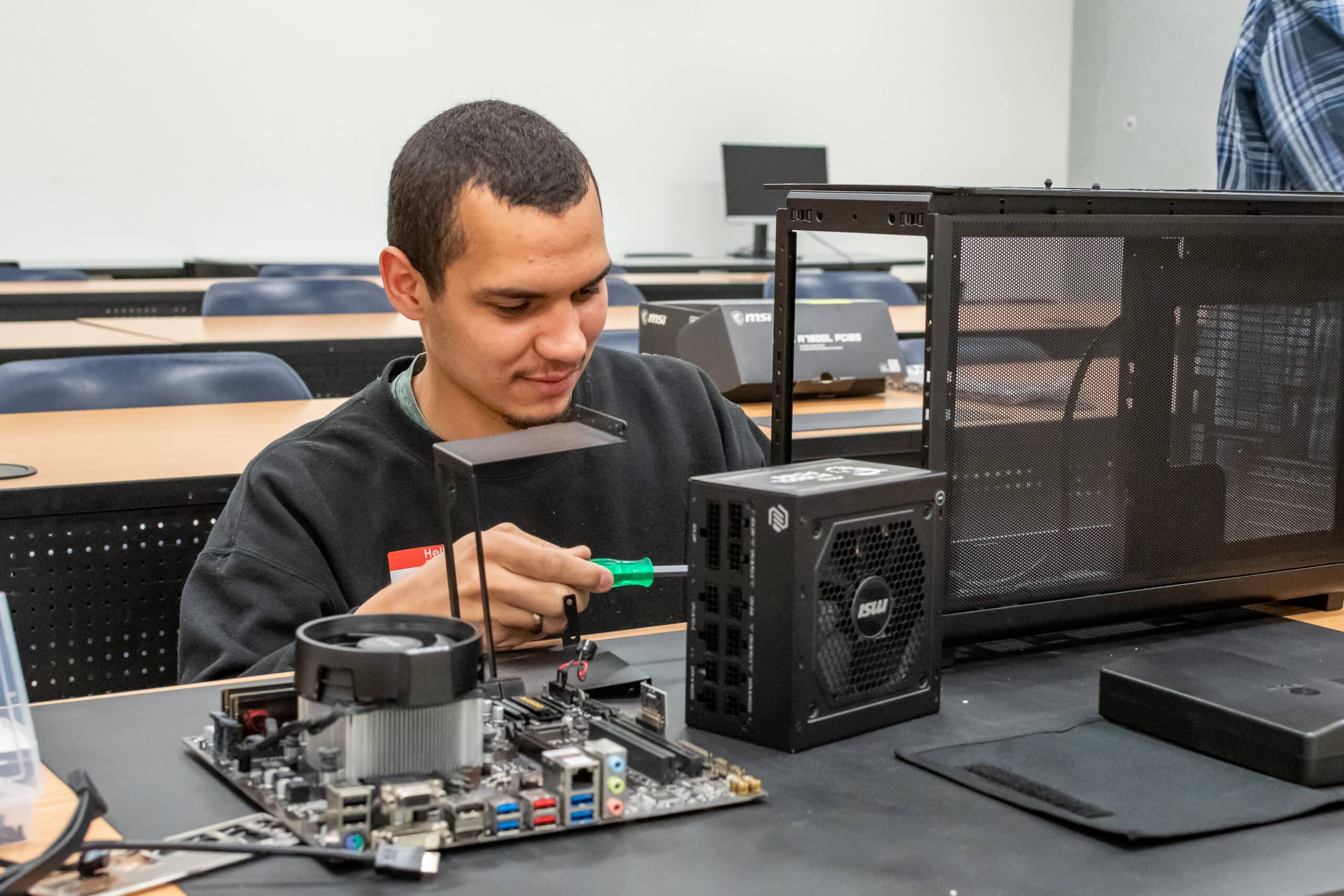 An ActivateWork learner working on assembling a desktop computer tower and motherboard.
